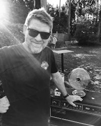 a black and white photo of a man with sunglasses standing next to an amp